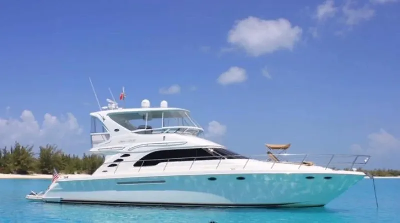 Slide: The Image of 2002 Sea Ray 56 Sedan Bridge yacht on clear blue water under a sunny sky. - 0