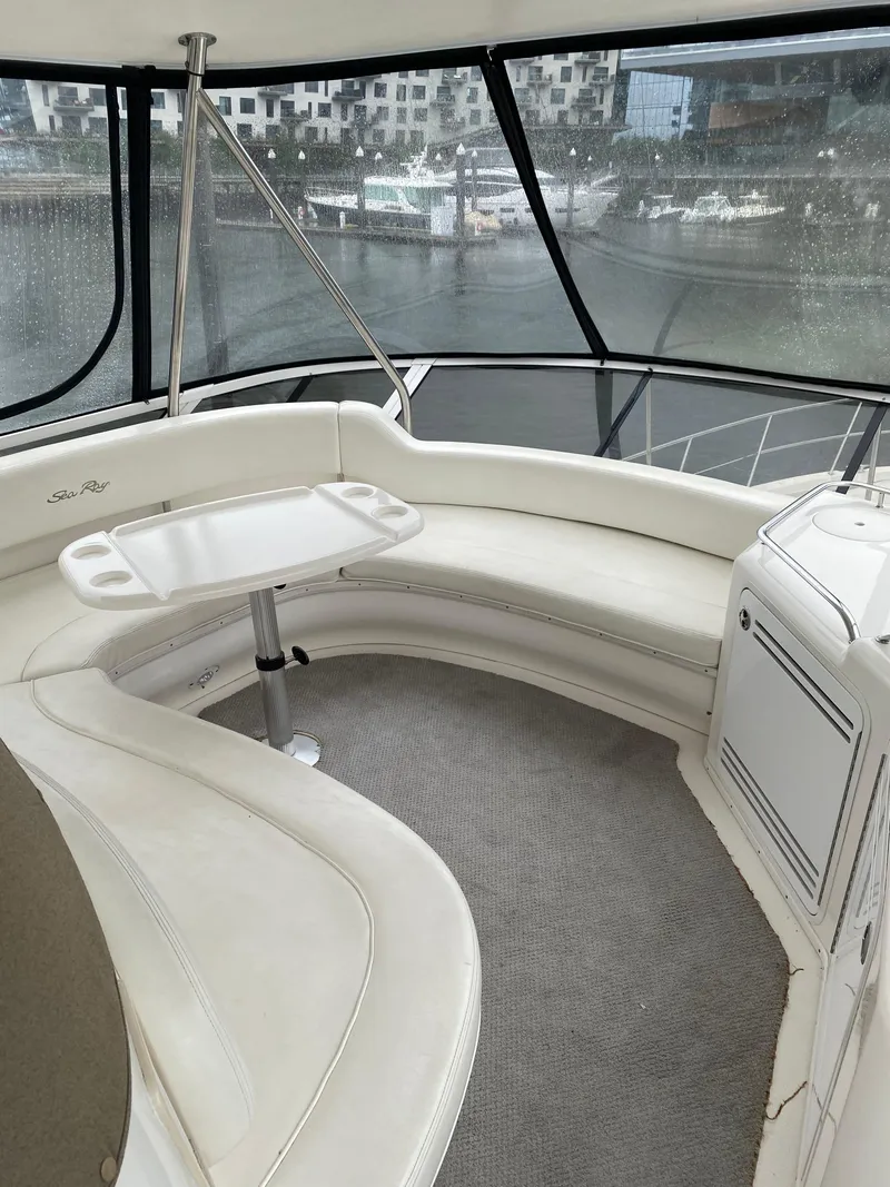 Slide: The Image of 2002 Sea Ray 56 Sedan Bridge interior with curved seating and table, overlooking marina. - 17