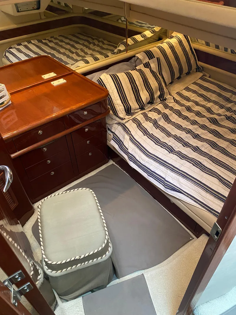 Slide: The Image of 2002 Sea Ray 56 Sedan Bridge cabin with striped bedding and wooden cabinetry. - 23