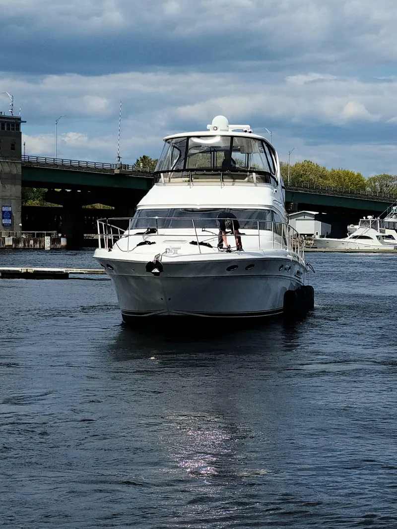 Slide: The Image of 2002 Sea Ray 56 Sedan Bridge yacht on a calm river under a cloudy sky. - 3