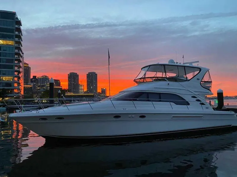 Slide: The Image of 2002 Sea Ray 56 Sedan Bridge yacht at sunset, city skyline in background. - 6