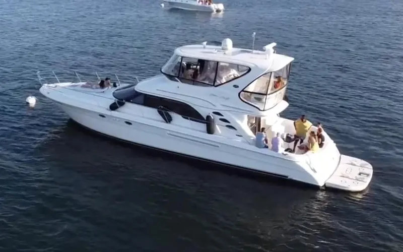 Slide: The Image of 2002 Sea Ray 56 Sedan Bridge yacht on calm water, with passengers enjoying the view. - 7