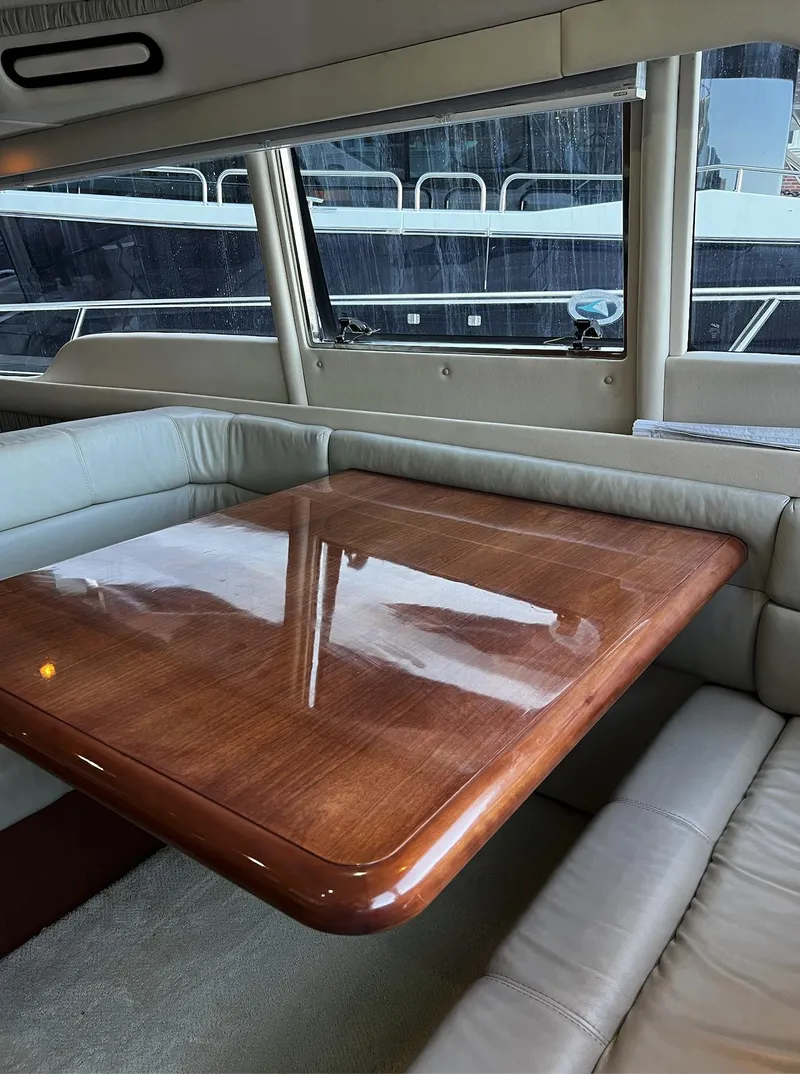 Slide: The Image of Interior of 2002 Sea Ray 56 Sedan Bridge with polished wooden table and leather seating. - 9