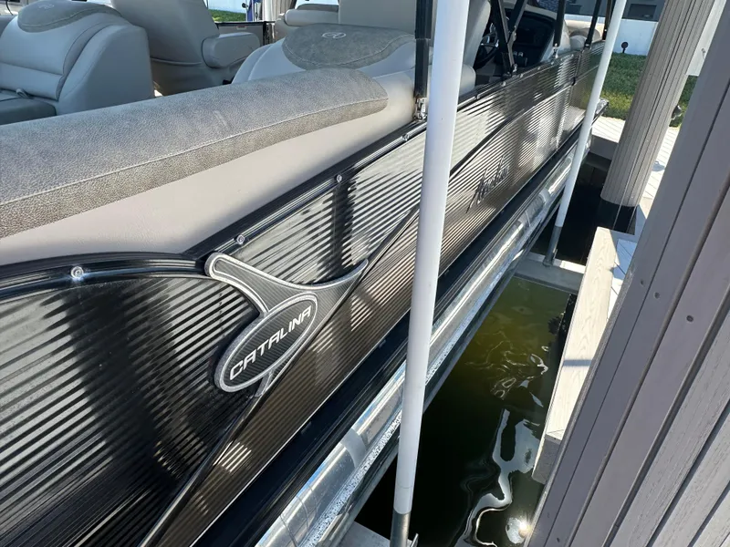 Slide: The Image of 2020 Avalon Catalina Platinum Quad Lounger boat docked, showcasing sleek design and comfortable seating. - 5