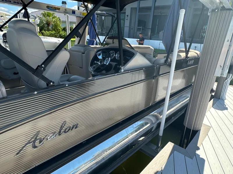Slide: The Image of 2020 Avalon Catalina Platinum Quad Lounger boat docked, showcasing sleek design and luxurious seating. - 6