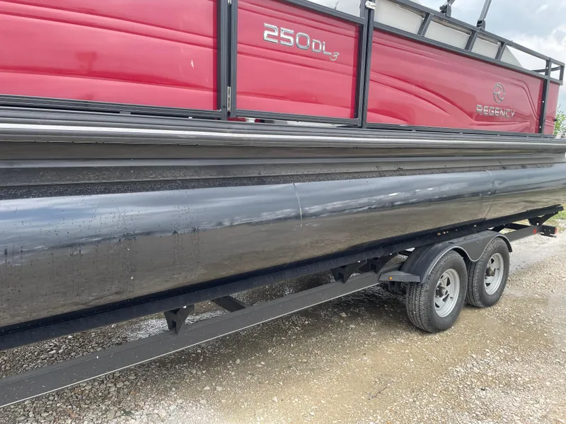 Slide: The Image of 2023 Regency 250DL3 pontoon boat on trailer, featuring red and black design. - 10