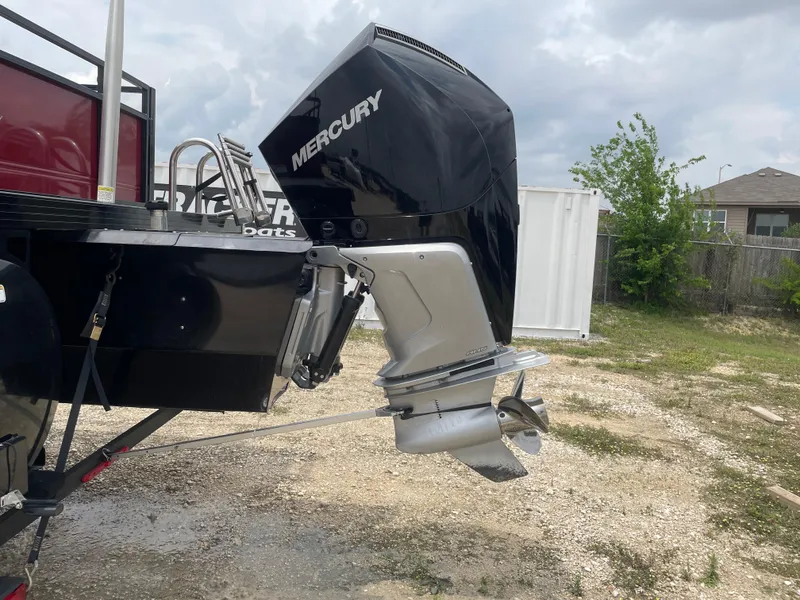Slide: The Image of 2023 Regency 250DL3 boat with Mercury outboard motor, parked on gravel with cloudy sky. - 11