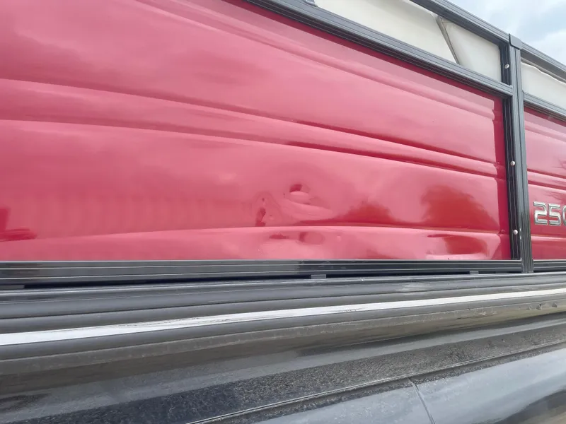 Slide: The Image of 2023 Regency 250DL3 boat with red exterior paneling and visible dent. - 12