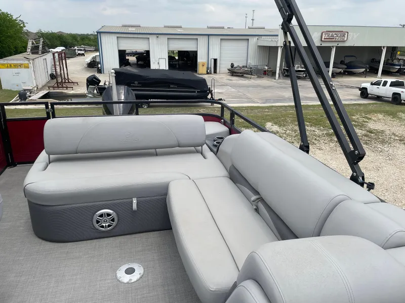 Slide: The Image of 2023 Regency 250DL3 pontoon boat with gray seating, docked near a service area. - 15