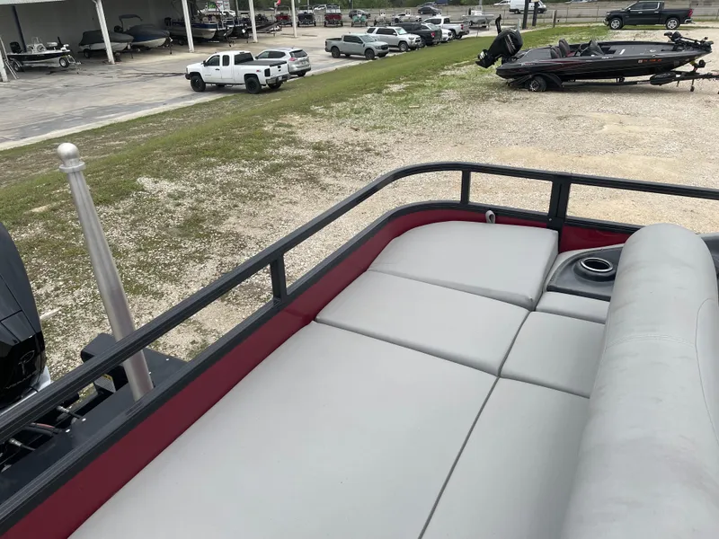 Slide: The Image of 2023 Regency 250DL3 pontoon boat with spacious seating and cup holder, parked outdoors. - 16