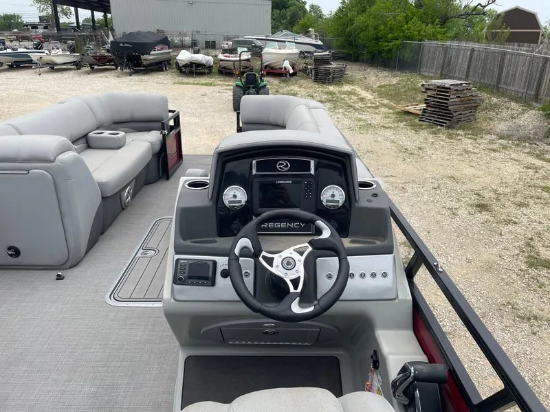 Slide: The Image of 2023 Regency 250DL3 pontoon boat interior with steering console and seating area. - 18