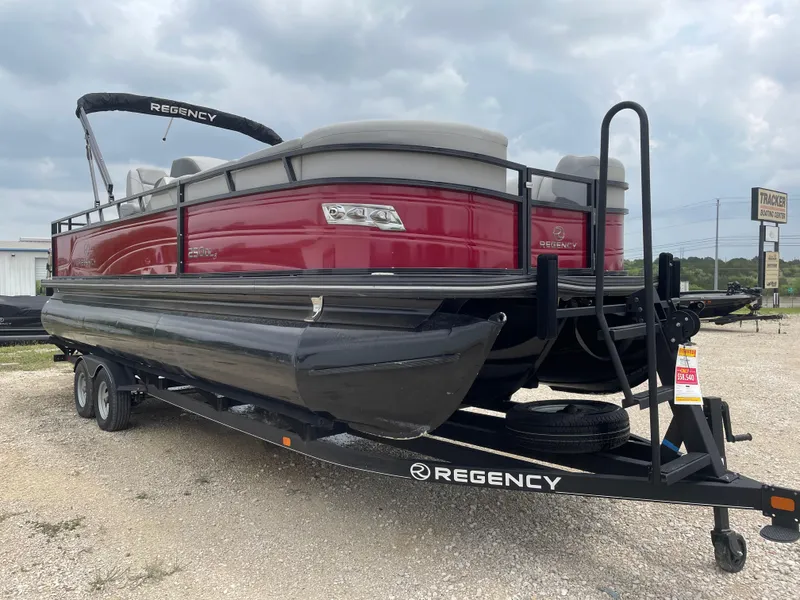 Slide: The Image of 2023 Regency 250DL3 pontoon boat on trailer, red and black design, parked outdoors. - 7
