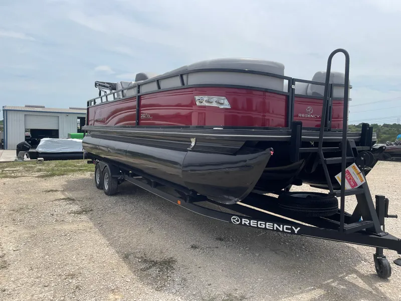 Slide: The Image of 2023 Regency 250DL3 pontoon boat on trailer, red and black design, parked outdoors. - 6