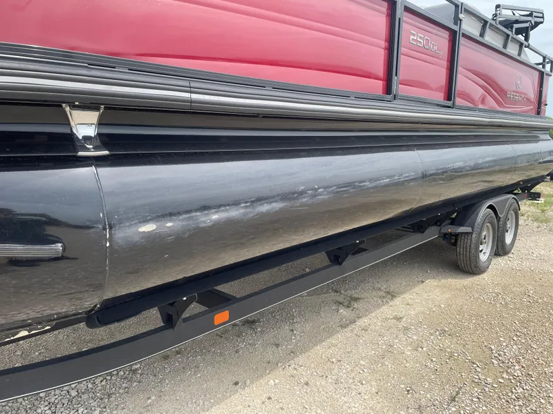 Slide: The Image of 2023 Regency 250DL3 pontoon boat on trailer, side view, red and black design. - 10