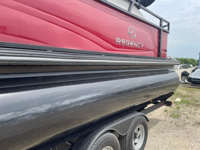 Slide: The Image of 2023 Regency 250DL3 pontoon boat on trailer, featuring red and black design. - 11