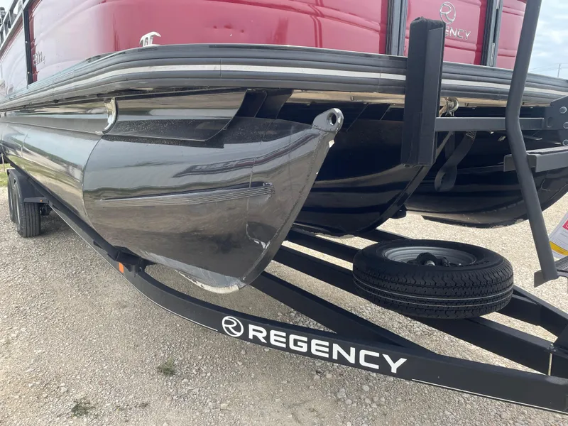 Slide: The Image of 2023 Regency 250DL3 pontoon boat on trailer, close-up of hull and logo. - 13