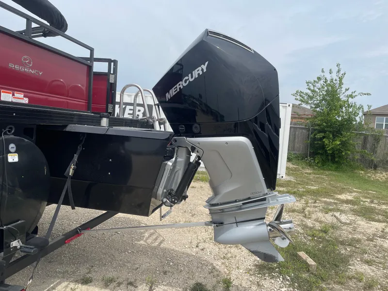 Slide: The Image of 2023 Regency 250DL3 boat with Mercury outboard motor, parked on gravel. - 3