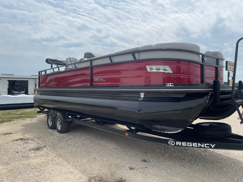 Slide: The Image of 2023 Regency 250DL3 pontoon boat on trailer, red and black design, parked outdoors. - 7
