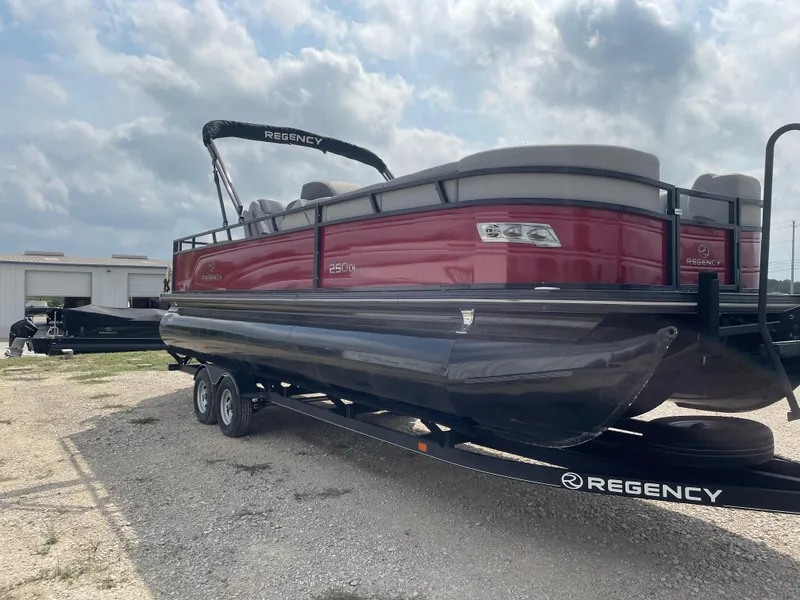 Slide: The Image of 2023 Regency 250DL3 pontoon boat on trailer, red and black design, parked outdoors. - 4