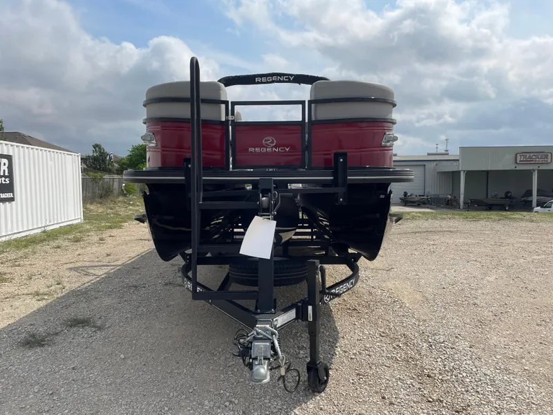 Slide: The Image of 2023 Regency 250DL3 pontoon boat on trailer, parked outdoors under cloudy sky. - 6