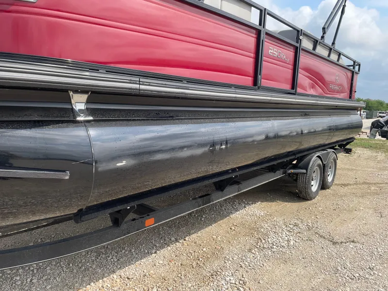 Slide: The Image of 2023 Regency 250DL3 pontoon boat with red and black design on a trailer. - 8