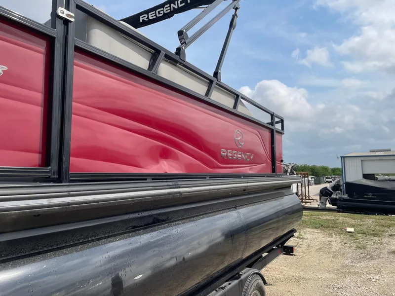 Slide: The Image of 2023 Regency 250DL3 pontoon boat with red and black exterior, parked outdoors. - 9