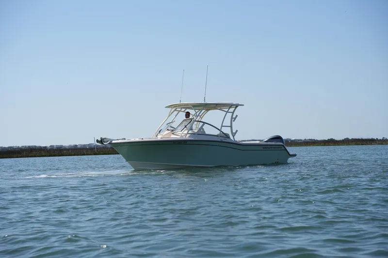 Slide: The Image of 2021 Grady-White Freedom 235 boat cruising on calm waters under clear skies. - 14