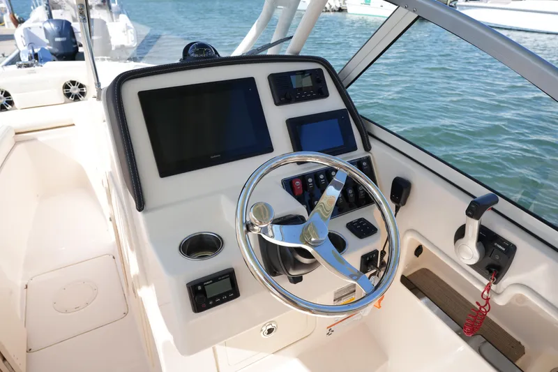 Slide: The Image of 2021 Grady-White Freedom 235 boat dashboard with steering wheel and navigation controls. - 23