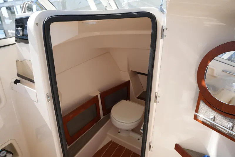 Slide: The Image of 2021 Grady-White Freedom 235 boat interior with compact marine toilet and wooden accents. - 30
