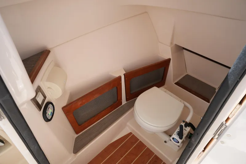 Slide: The Image of 2021 Grady-White Freedom 235 boat interior with compact marine toilet and wooden accents. - 31