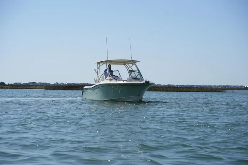 Slide: The Image of 2021 Grady-White Freedom 235 boat cruising on calm waters under clear sky. - 5