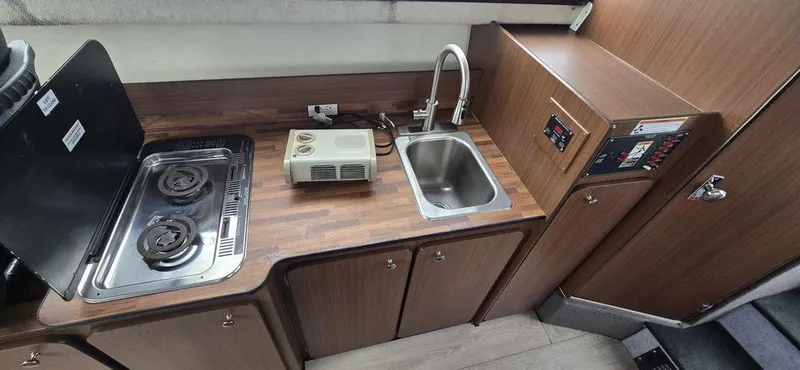 Slide: The Image of 1994 Bayliner 2858 Cierra boat kitchen with stove, sink, and wooden cabinetry. - 13