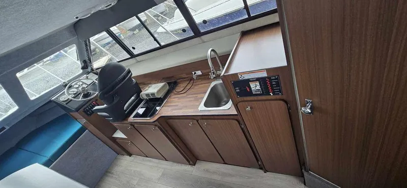 Slide: The Image of Interior of 1994 Bayliner 2858 Cierra boat with helm, kitchenette, and seating area. - 7