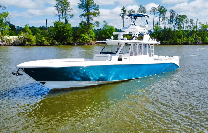 The Image of 2016 Everglades 435 Center Console boat on a calm river with lush greenery. - 0