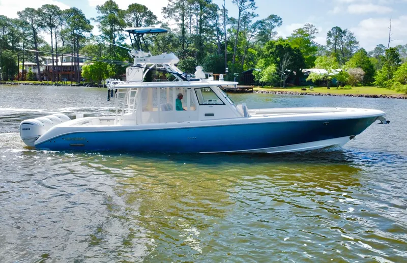 Slide: The Image of 2016 Everglades 435 Center Console boat on a calm lake with trees in the background. - 10