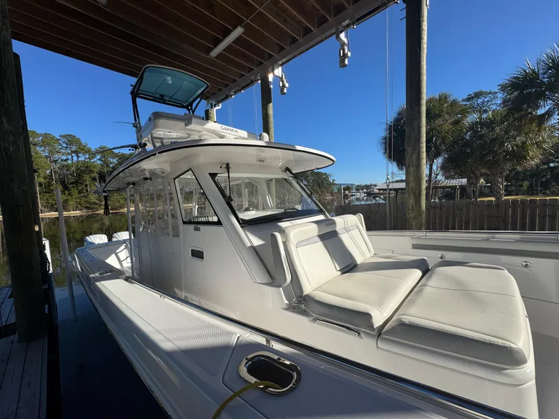 Slide: The Image of 2016 Everglades 435 Center Console boat docked under a canopy, featuring sleek white seating. - 30