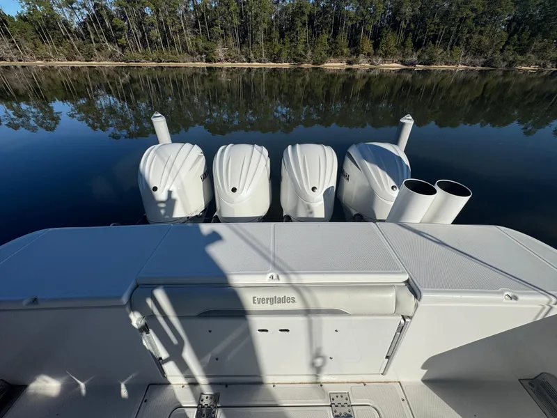 Slide: The Image of 2016 Everglades 435 Center Console boat with four engines, docked by a calm lake. - 42