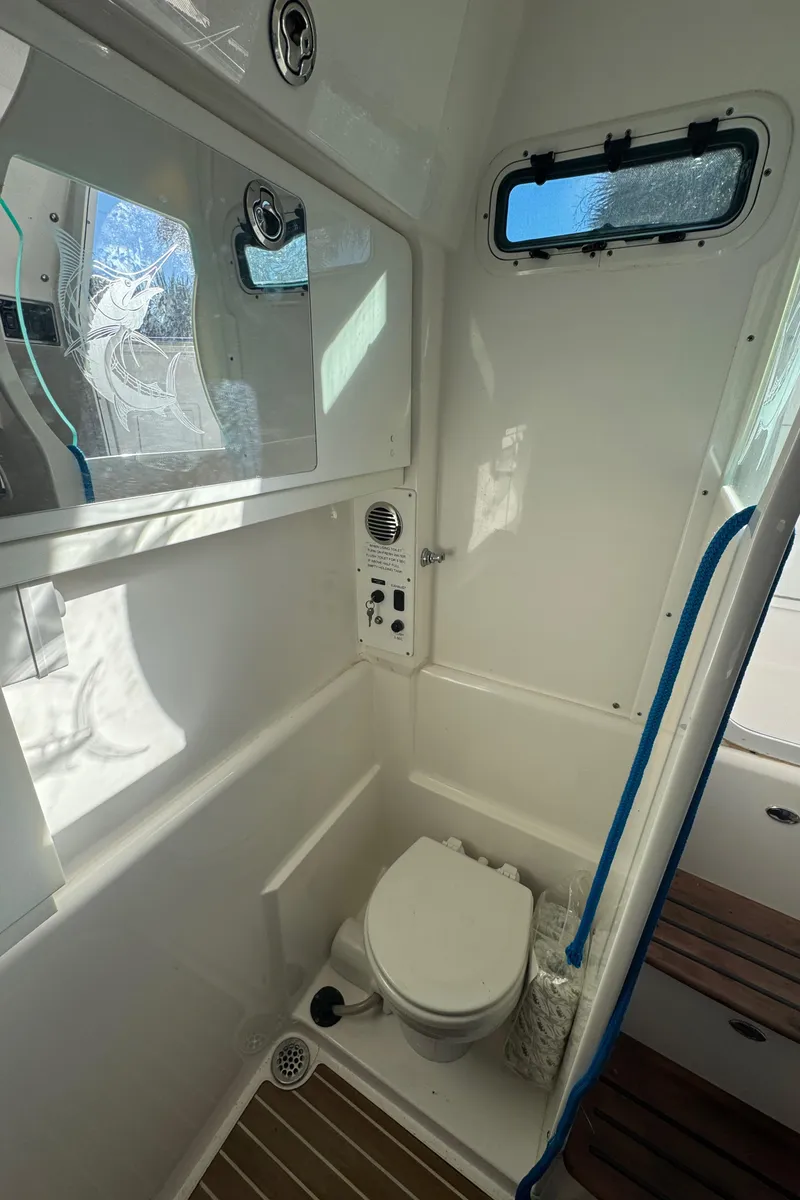 Slide: The Image of 2016 Everglades 435 Center Console boat bathroom with toilet and window. - 56