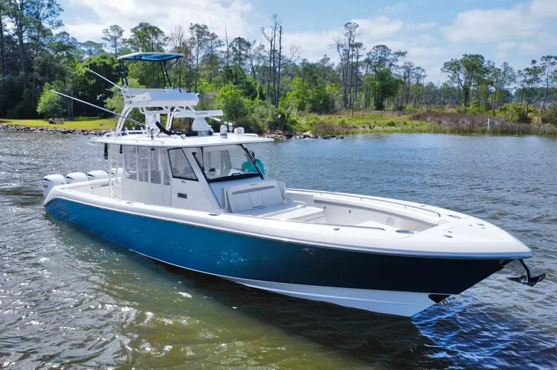 Slide: The Image of 2016 Everglades 435 Center Console boat on a serene lake with lush greenery. - 9