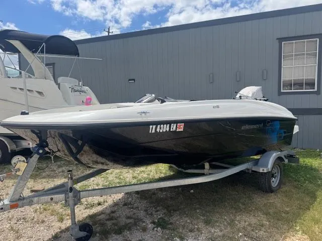 Slide: The Image of 2019 Bayliner Element E16 boat on trailer, parked outdoors near a building. - 1