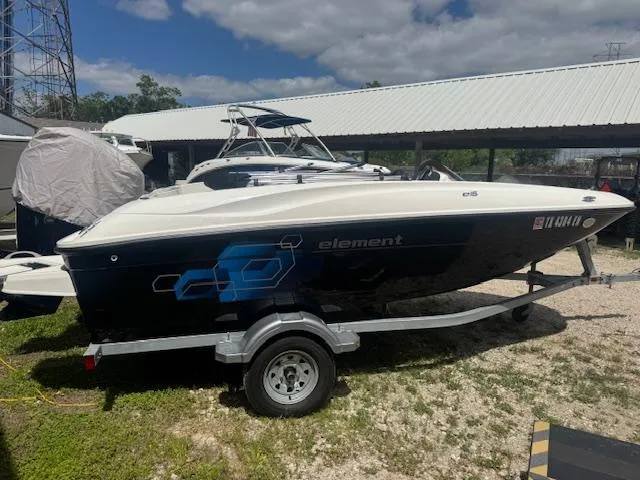 Slide: The Image of 2019 Bayliner Element E16 boat on trailer, parked outdoors under a cloudy sky. - 2