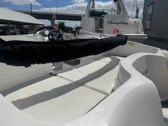 Slide: The Image of 2019 Bayliner Element E16 boat interior with seating and steering wheel, docked under a bridge. - 7