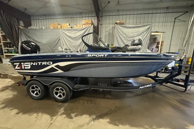 Slide: The Image of 2024 Nitro ZV19 Sport boat in a garage, showcasing sleek design and dual-axle trailer. - 3