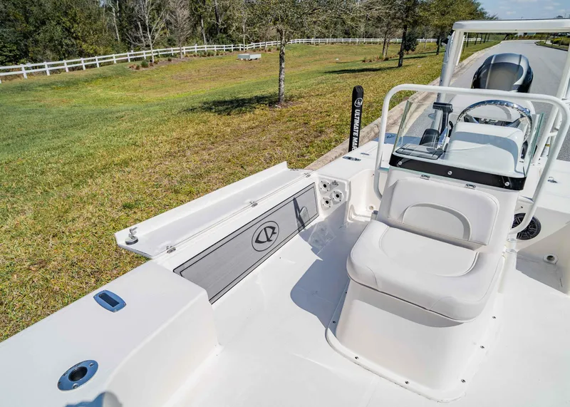 Slide: The Image of 2024 Spyder FX 19 Vapor boat interior with seating and console, parked near grassy area. - 9