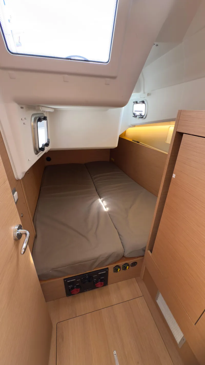Slide: The Image of Interior cabin of 2022 Jeanneau Sun Odyssey 410 sailboat, featuring a cozy bed and wooden finish. - 16