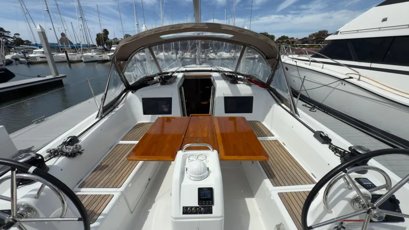 Slide: The Image of 2022 Jeanneau Sun Odyssey 410 sailboat cockpit with dual steering wheels and wooden table. - 3