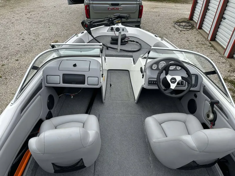 Slide: The Image of 2009 Skeeter SL 190 boat interior with gray seats and steering wheel, parked near a truck. - 39