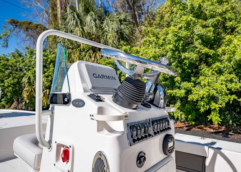 Slide: The Image of 2024 Spyder FX 19 Vapor boat console with Garmin system, surrounded by lush greenery. - 10