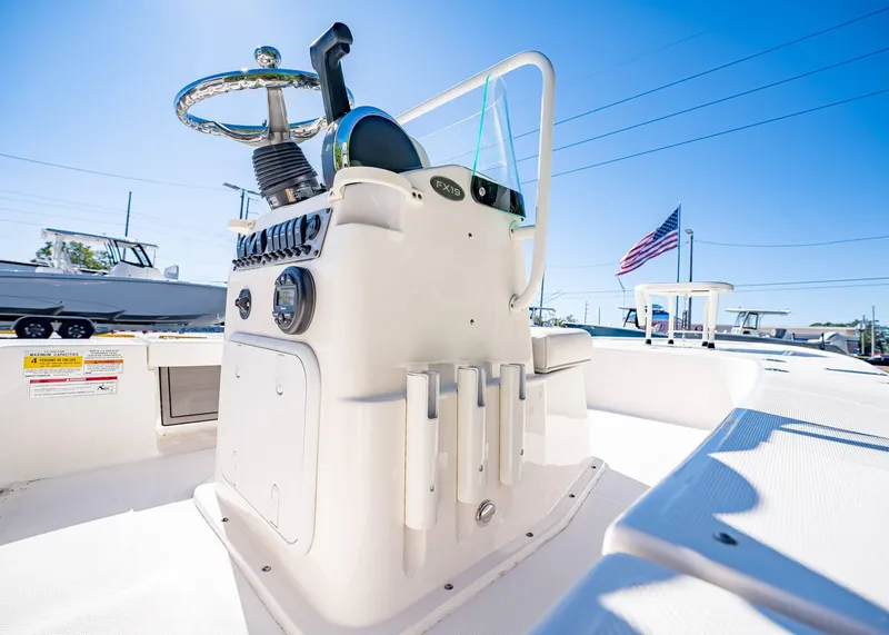 Slide: The Image of 2024 Spyder FX 19 Vapor boat console with steering wheel, rod holders, and American flag in background. - 17