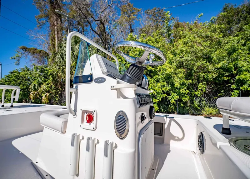 Slide: The Image of 2024 Spyder FX 19 Vapor boat console with steering wheel, set against lush greenery. - 9